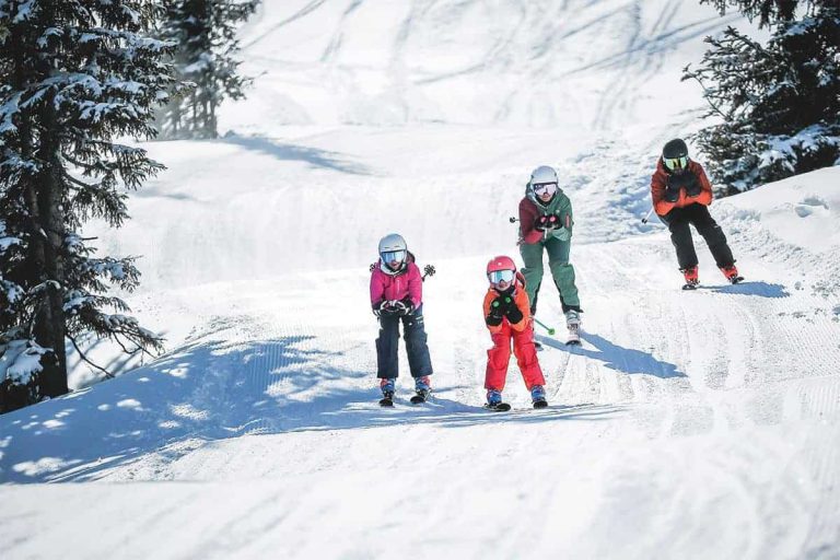 Familien beim Skifahren auf einer verschneiten Piste in den Kitzbüheler Alpen.