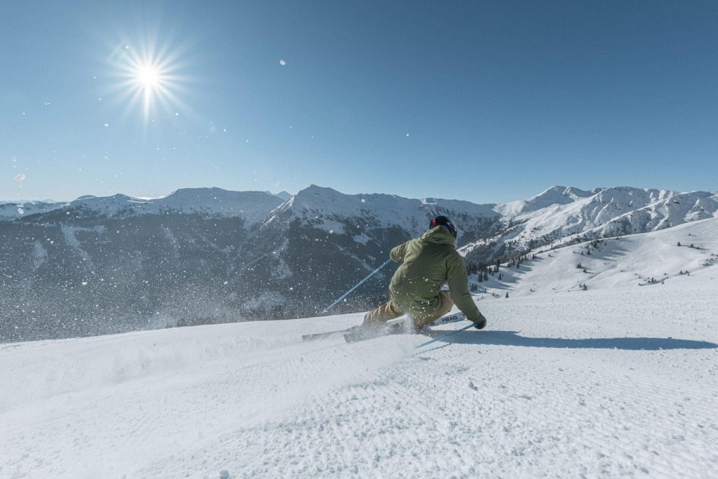 Skifahrer auf unberührter Piste vor alpiner Winterlandschaft in Saalbach Hinterglemm.