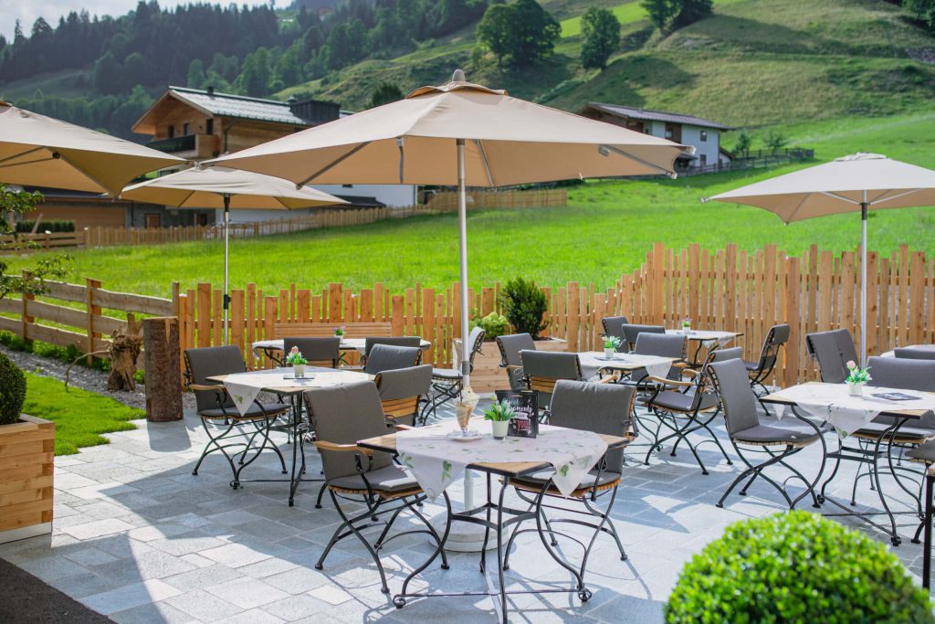Terrasse des Hotel Barbarahof mit Tischen und Sonnenschirmen, umgeben von grüner Wiese.