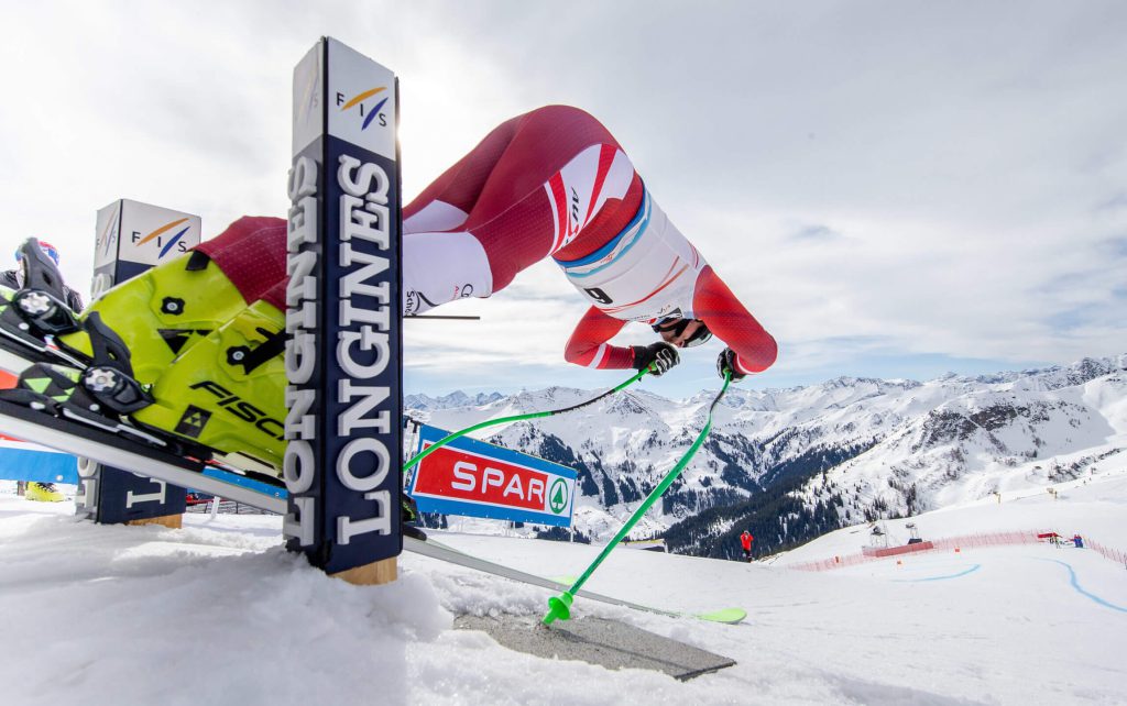 Skifahrer springt in den Kitzbüheler Alpen, umgeben von schneebedeckten Bergen.