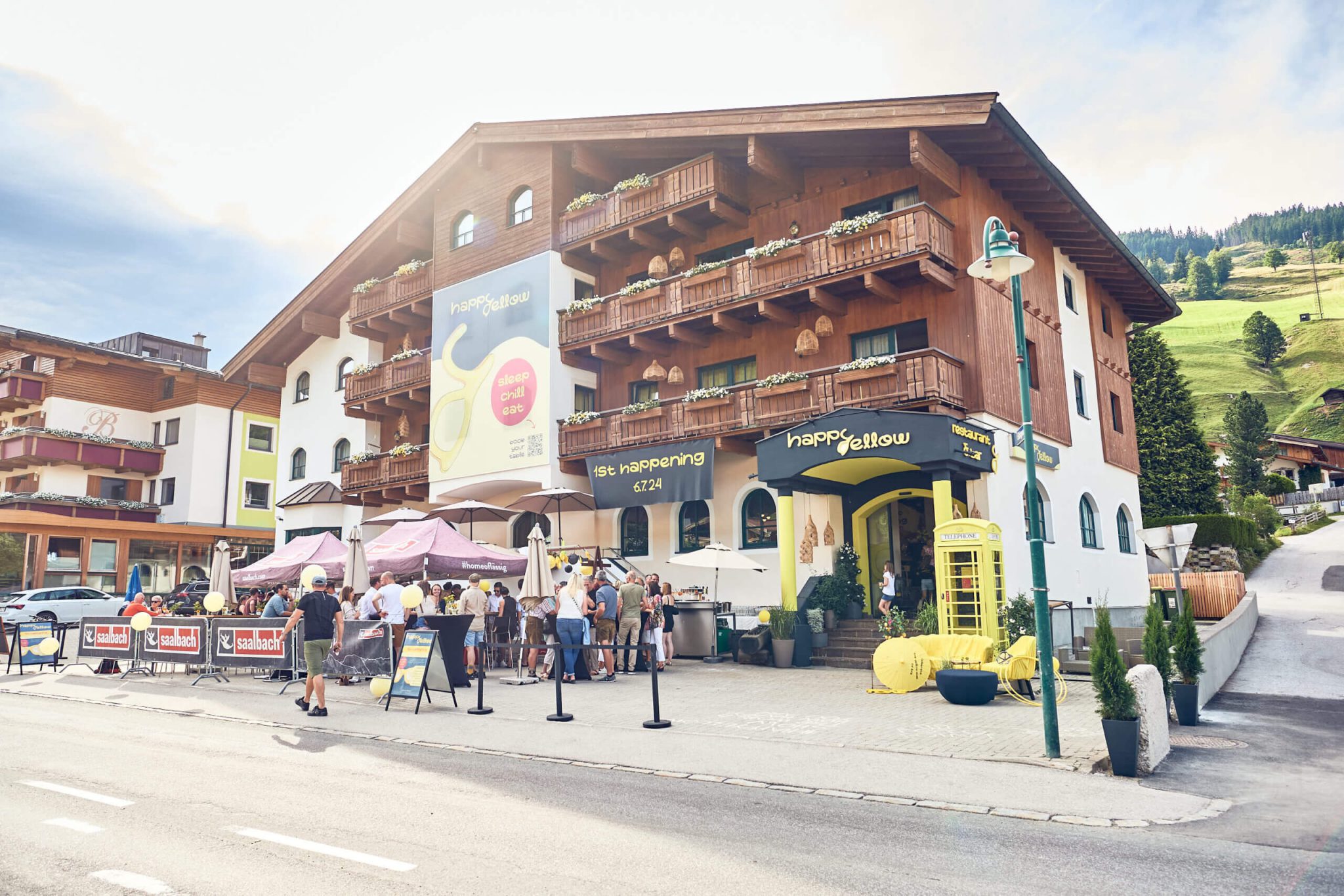 Hotelansicht mit Gästen im Freien, umgeben von Bergen in Saalbach Hinterglemm.